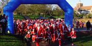 Runners dressed as Santa passing through starting archway of David Randall Foundation