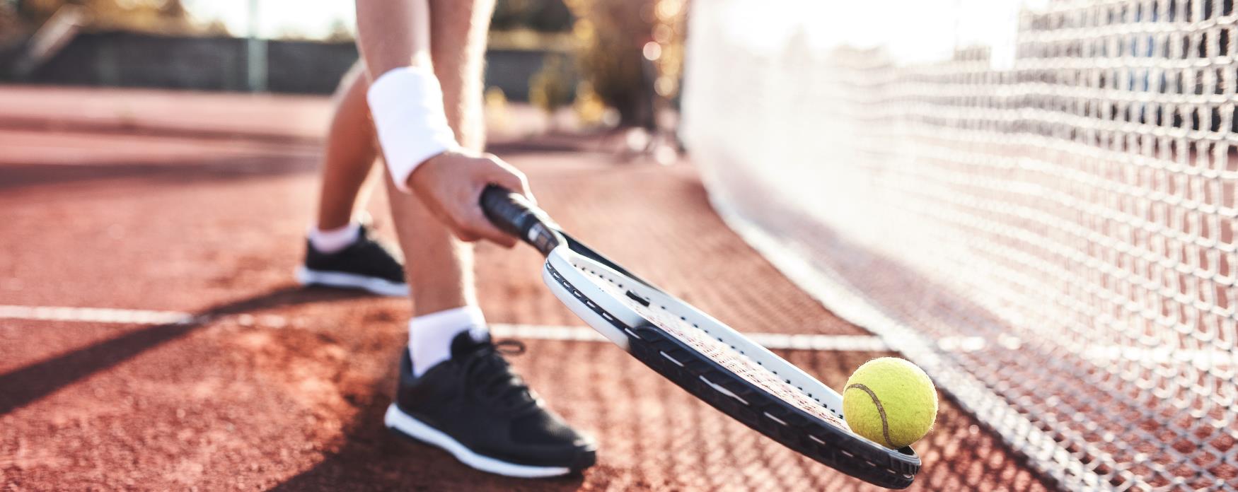Tennis player picking up a tennis ball