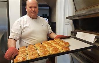 Baker taking a tray of freshly made scones out of the oven