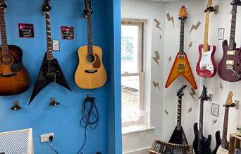 Display of acoustic and electric guitars on the wall