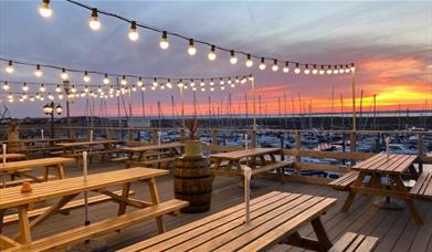 Outside seating at Bradwell Marina Bar & Restaurant, lit up in early evening
