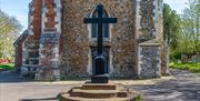 Wooden cross of Tollesbury war memorial in front of church