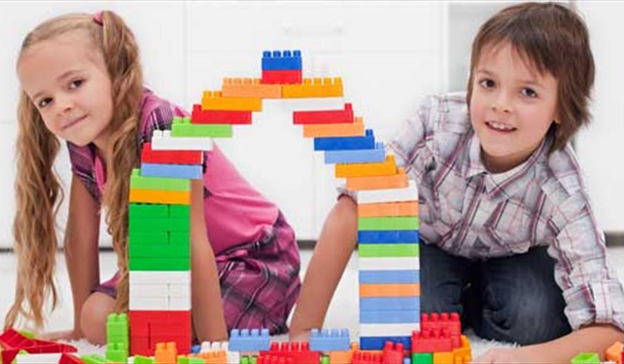 A boy and girl building a bridge with coloured blocks