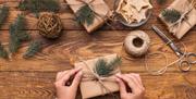 Christmas present being wrapped with eco-wrapping paper, string and natural foliage