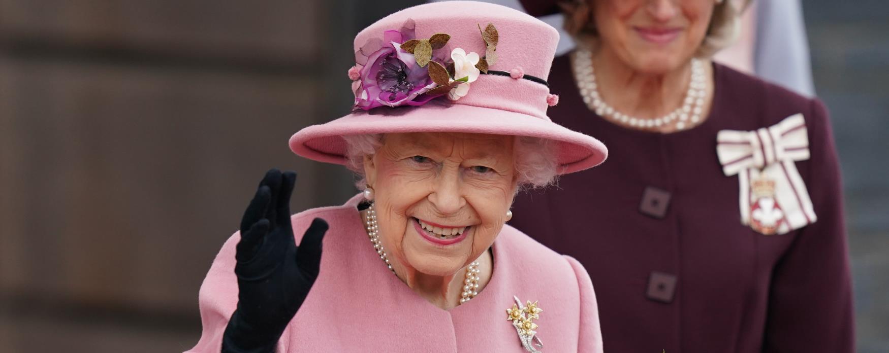Picture of Queen Elizabeth II wearing a pink hat with flowers on and smiling happily