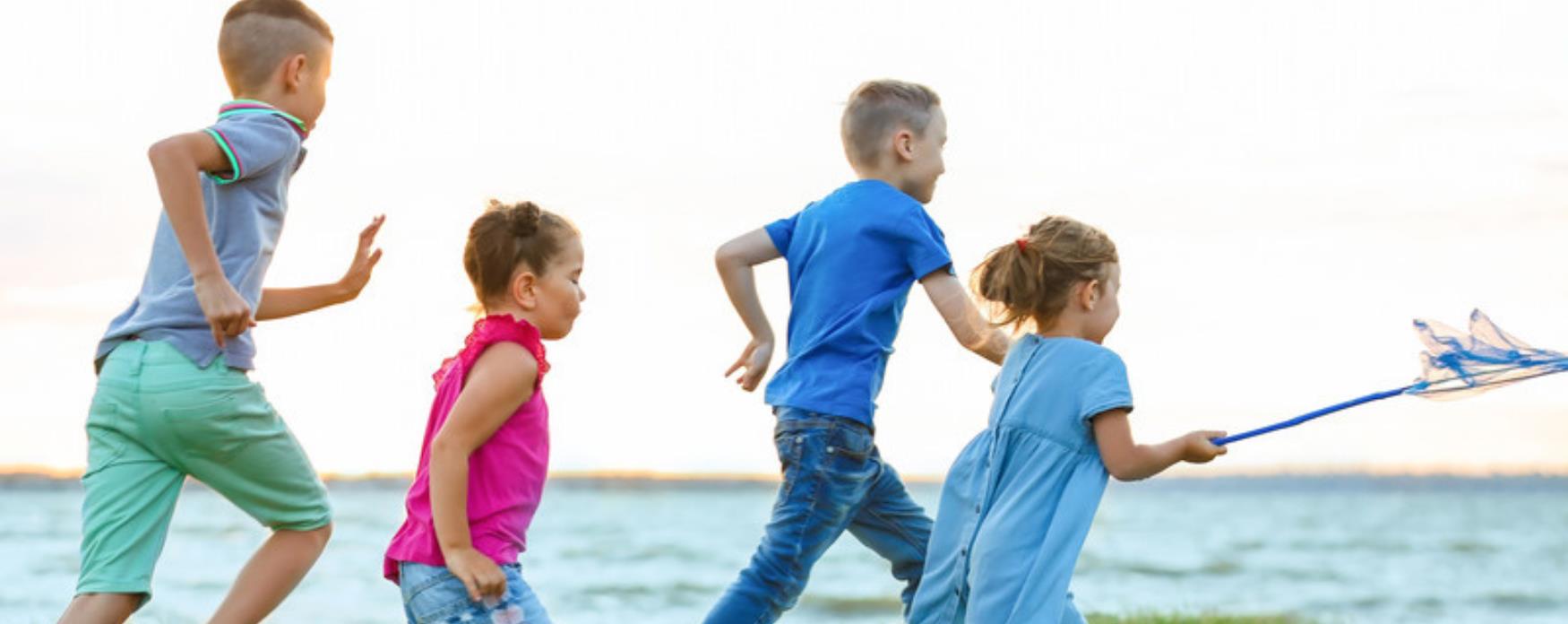 Children running towards a beach looking happy