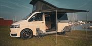 Camper van with awning and pop up roof, with deckchairs and awning out