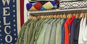 Rows of vintage military jackets by Welcome sign at Hang Up Vintage