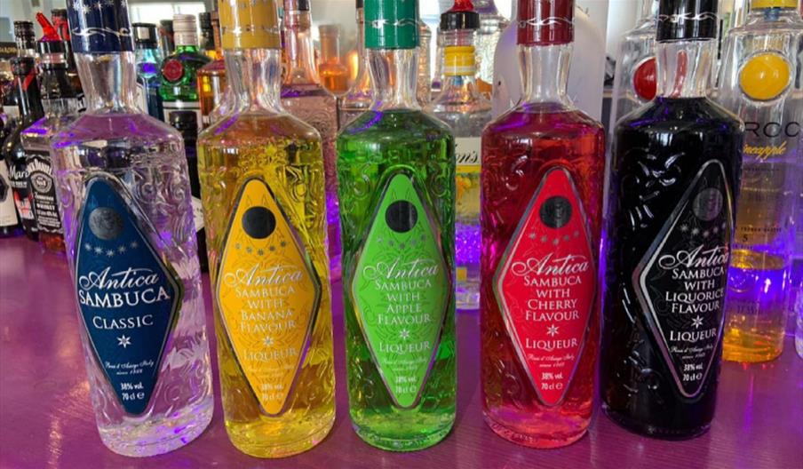 array of colourful bottles of Sambucca and other spirits