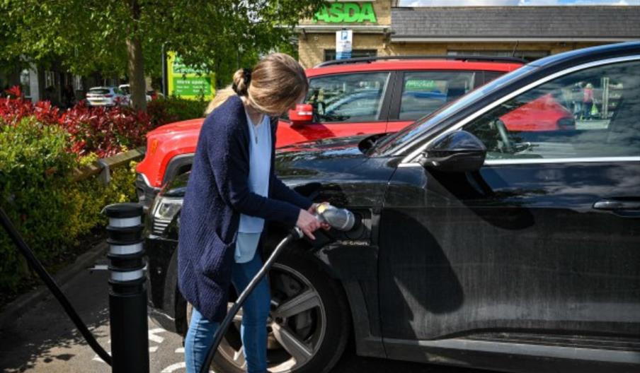 Woman putting electric car on charge at Asda store