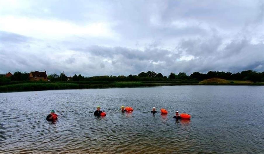 Members of Blackwater Triathlon club open water swimming in a large lake