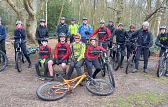 Group of teenage cyclists and leaders mountain biking in woods