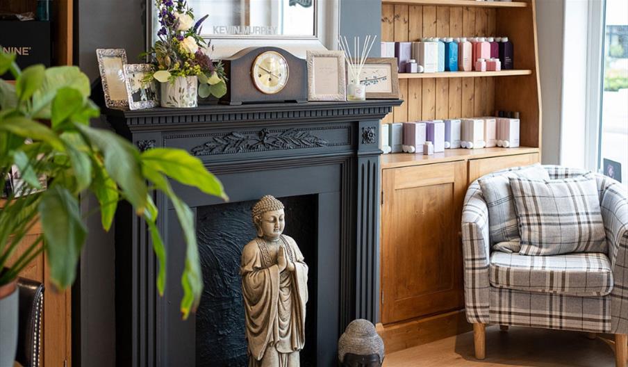 Chandlers Hair Studio with fireplace, comfortable chair, wooden dresser, plants and Buddha statue
