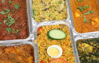 selection of foil dishes of different takeaway curry and rice items