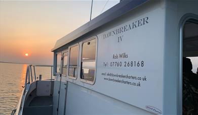 Dawn Breaker charter fishing boat sailing into the sunset