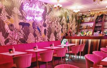 Ginny's Cocktail Lounge with pink chairs and jungle themed walls