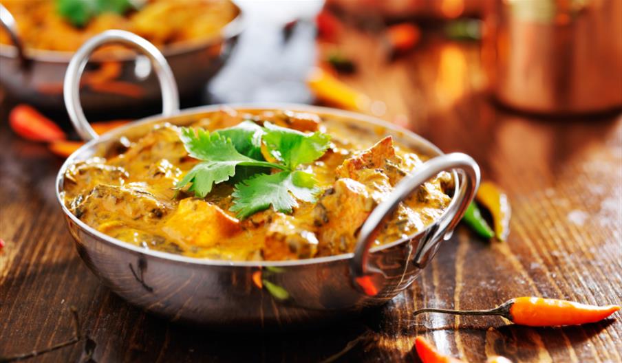 Curry served in a metal dish with a sprinkling of coriander