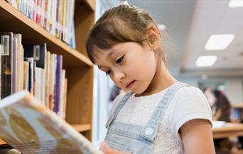Young girl reading a library book