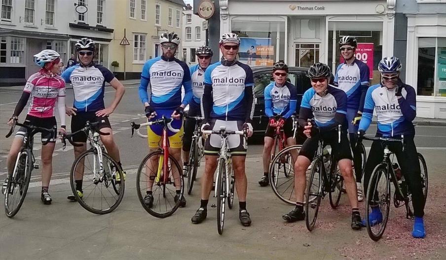 Group of male and female cyclists in uniform of Maldon and District Cycling Club, meeting in Maldon High Street