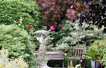 Beautiful garden with statues, bench and flowers
