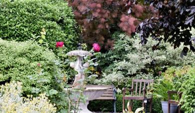 Beautiful garden with statues, bench and flowers