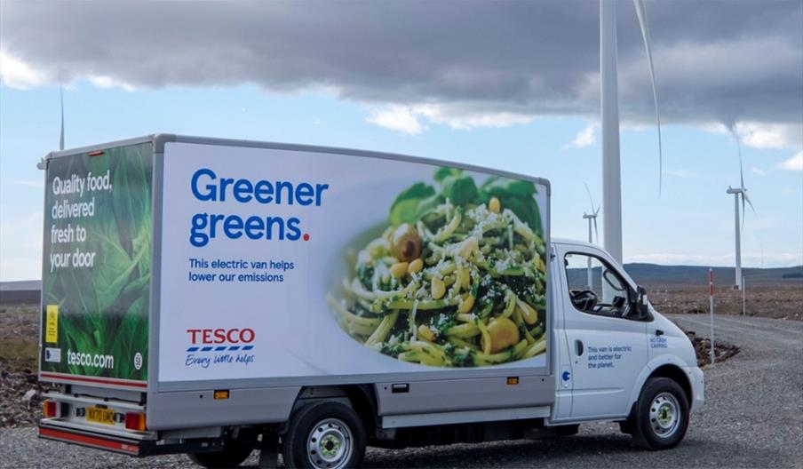 Electric Tesco delivery van in front of wind farm
