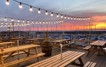 Outside seating at Bradwell Marina Bar & Restaurant, lit up in early evening
