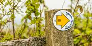 Public footpath sign fixed to a rustic wooden fence