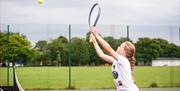 A young girl serving a tennis shot.