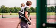 A father and daughter walking onto the tennis courts