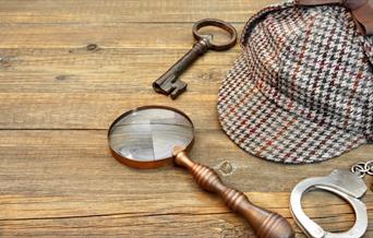 A selection of Sherlock Holmes' items including a hat and magnifying glass