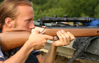 A man aiming down the sights of an air rifle